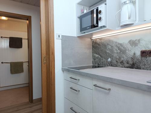 a kitchen with white cabinets and a microwave at Apartments im Jagdhof in Fischen