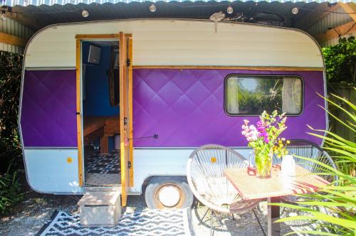Caravana de color púrpura y blanco con mesa y sillas en Retro Caravans at Valentia Island Escape en Valentia Island