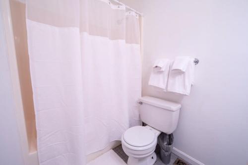 a white bathroom with a toilet and a shower at Sojourn Tree Lined Streets Newport News in Newport News