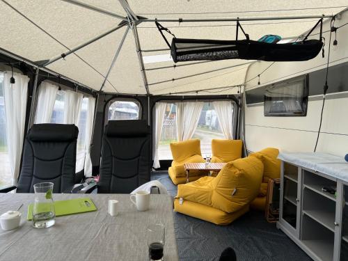 a tent with yellow chairs and a table in it at przyczepa in Jastarnia