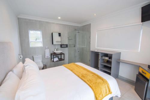 Le Rubis Guesthouse في Van Riebeekhoogte: غرفة نوم بسرير ابيض كبير وحمام