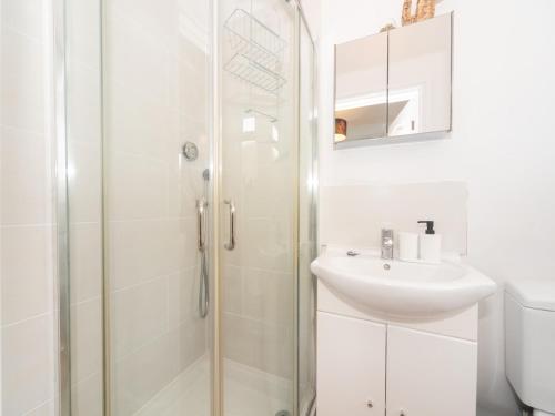 een witte badkamer met een douche en een wastafel bij Elegant bright flat free parking Pass the Keys in Kingston upon Thames