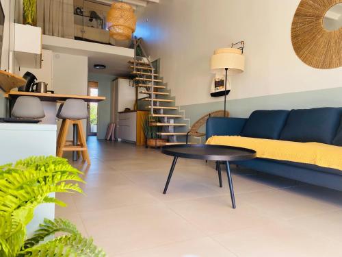 un salon avec un canapé bleu et une table dans l'établissement VILLA NATURISTE HELIOVILLAGE - CAP D'AGDE - 4 PERS, au Cap d'Agde