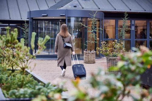 a woman walking with a suitcase in front of a building at Hotel Odense in Odense