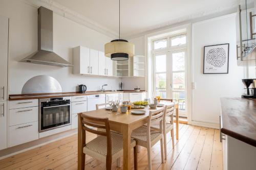 a kitchen with a wooden table and chairs and a kitchen with white cabinets at Perfect Holiday Homes Near Amager Beach in Copenhagen
