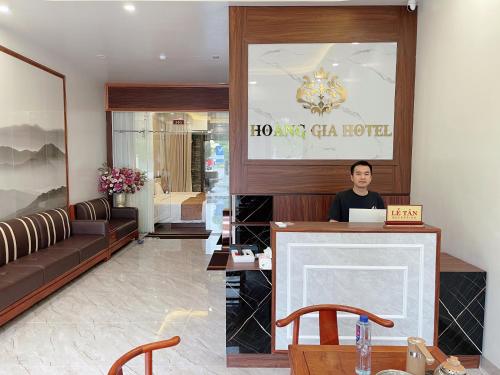 Ein Mann, der an einem Schreibtisch in einer Hotellobby sitzt. in der Unterkunft HOÀNG GIA HOTEL in Móng Cái