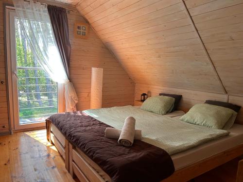 a bed in a wooden room with a large window at Resort EDEN - domki, pokoje, apartamenty in Jastrzębia Góra