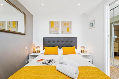 une chambre avec un grand lit avec des oreillers jaunes dans l'établissement Downtown Cannes Modern 1-Br Apartment, à Cannes