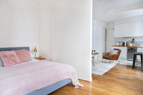 une chambre avec un lit rose et une cuisine dans l'établissement Le Plaisir du Pantheon, à Paris