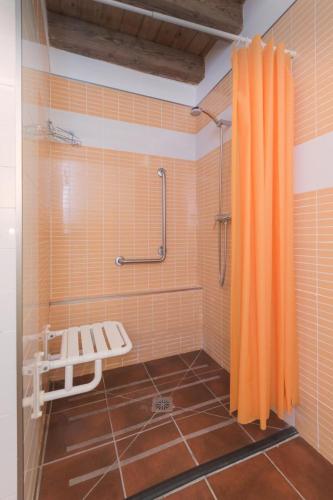 a shower with an orange curtain in a bathroom at blasón conde de castro in Santo Tomé de Zabarcos