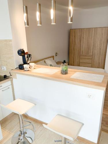 Eine Küche mit weißer Arbeitsplatte und zwei Hockern in der Unterkunft Super Central Chic Studio-free coffee, self check in & check out in Oradea