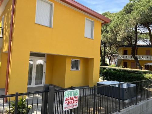 a yellow house with a sign in front of it at Principesse in Rosolina Mare
