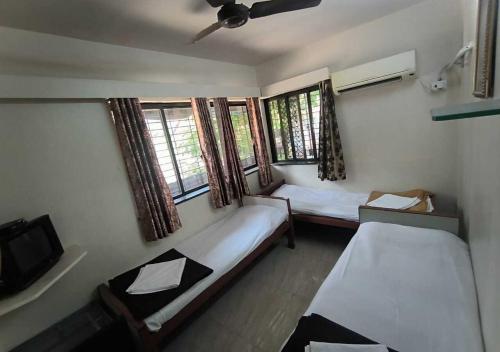 um pequeno quarto com duas camas e uma televisão em Hotel Rupali em Mumbai