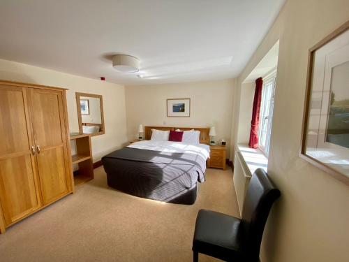 1 dormitorio con 1 cama y 1 silla en The Globe Inn en Kingsbridge