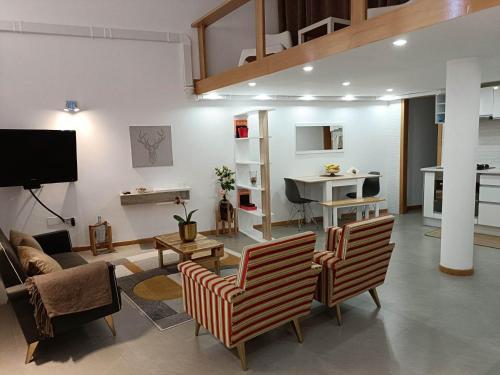 ein Wohnzimmer mit 2 Stühlen, einem Sofa und einem Klavier in der Unterkunft mezzanino Ribeira Brava in Vila da Ribeira Brava