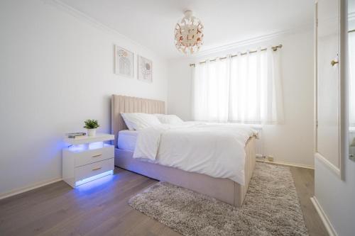 a white bedroom with a bed and a window at Luxurious 2-Bed House in Dartford in Dartford