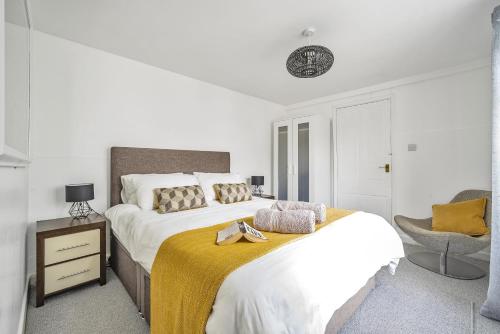 a white bedroom with a large bed and a chair at Waters Edge Holiday Home in Hayle, West Cornwall in Hayle