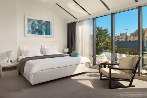 a white bedroom with a bed and a chair at Hotel Atrium in Split