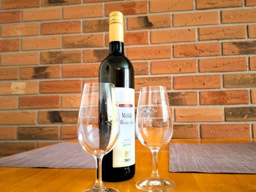 - une bouteille de vin et 2 verres à vin sur une table dans l'établissement Penzión Villa Agnes, à Smolenice