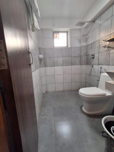 a small bathroom with a toilet and a window at Date Palm Home Stay in Tezpur