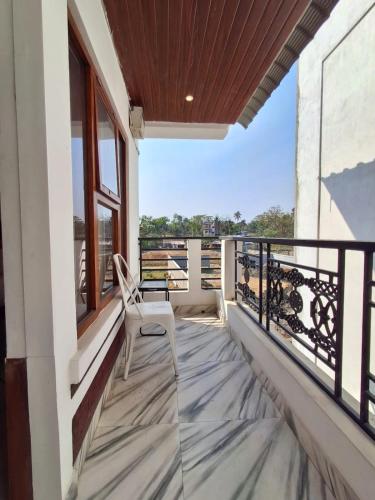 a white chair sitting on the balcony of a house at Date Palm Home Stay in Tezpur