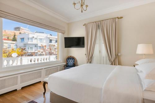 a bedroom with a large white bed and a large window at Noble Suites in Athens