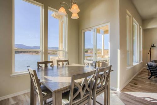 a dining room with a table and chairs and windows at Luxury Lake House With Mountain Views & Hot Tub in Monument