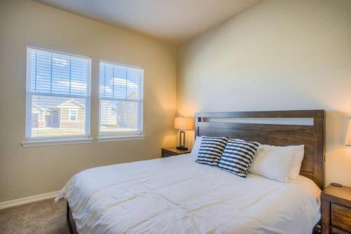 a bedroom with a bed with two pillows and two windows at Luxury Lake House With Mountain Views & Hot Tub in Monument