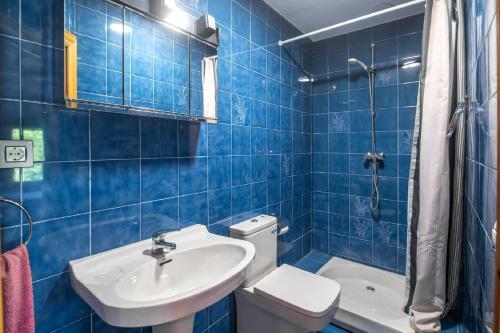 a blue tiled bathroom with a toilet and a sink at Villa Selina Llanes – Terraza, Vista y Playa Cerca in La Pereda de Llanes