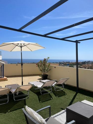 a patio with chairs and an umbrella on a roof at Panoramic Seaview in Mijas
