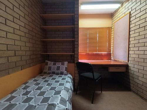 a bedroom with a bed and a desk and a window at Orlando Hotel in Soweto
