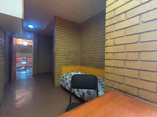a room with a bed against a brick wall at Orlando Hotel in Soweto
