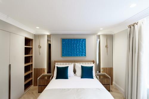 a bedroom with a large white bed with blue pillows at Holland Park Residence in London
