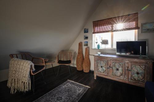 a living room with a tv and a wooden entertainment center at Bed and Relax Terschelling in Midsland