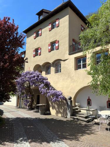 un edificio con un montón de flores púrpuras en él en Weingut Köfelgut - Turris Vini en Castelbello