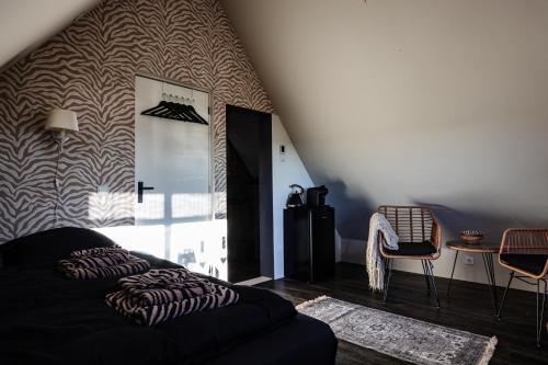 a living room with a black couch and a wall at Bed and Relax Terschelling in Midsland