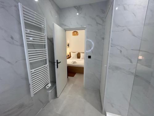 La salle de bains blanche est pourvue d'une douche à l'italienne et d'une porte. dans l'établissement Palais de France Classic Charm, à Beausoleil