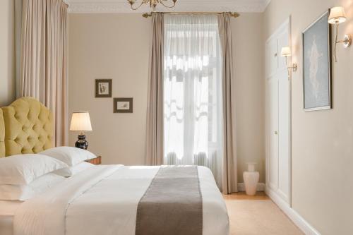 a white bedroom with a large bed and a window at Noble Suites in Athens