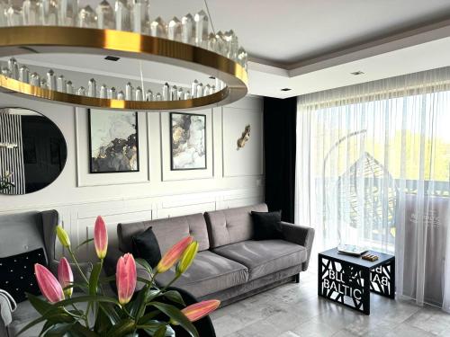 a living room with a couch and a chandelier at Apartamenty BLUE BALTIC SPA Jacuzzi & Sauna MORZE in Chłopy