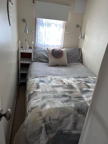 a bed in a small room with a window at Chalet 71 in Leysdown-on-Sea