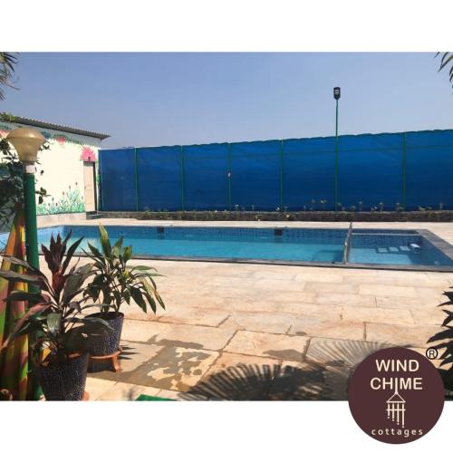 a swimming pool in front of a blue building at Windchime Cottages in Alibaug