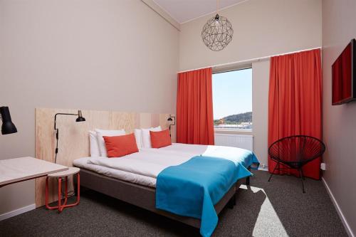 a bedroom with a bed with red curtains and a window at Kviberg Park Hotel & Conference in Gothenburg