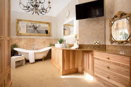 bagno con vasca, lavandino e specchio di The Bothy at Dryburgh a Saint Boswells