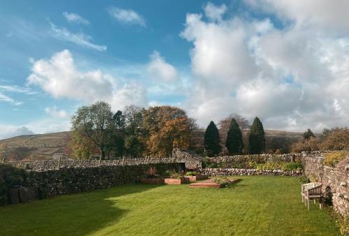 a garden with a stone wall and a grass yard at The Art House in Arncliffe