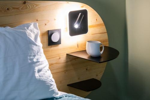 - un lit avec une tête de lit et une tasse sur une table dans l'établissement Suite Kella Tassin - Beau studio rénové, à Tassin-la-Demi-Lune