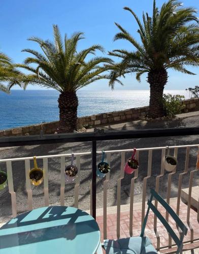a balcony with a table and palm trees and the ocean at Bellissima Cervo in Cervo