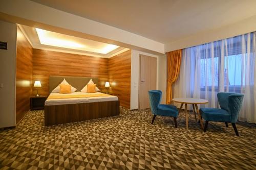 a hotel room with a bed and two chairs and a table at No 107 Predeal in Predeal