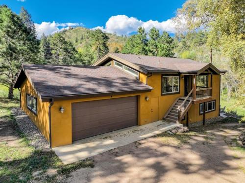 a small yellow house with a garage at Green Mt Getaway Hot Tub Game Room & Fire Pit in Cascade-Chipita Park