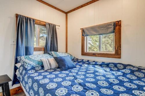 Cama azul en habitación con 2 ventanas en Prairie Place, en Palmer Lake