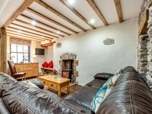 a living room with a leather couch and a fireplace at Blacksmiths Cottage in Pembroke